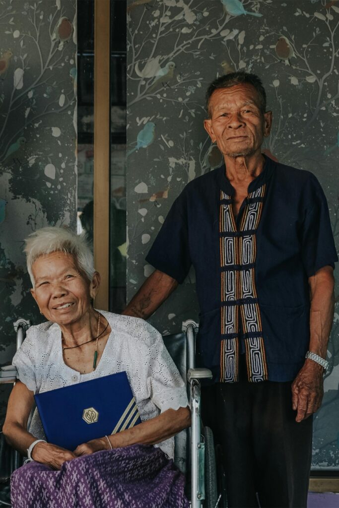 An elderly couple smiling together, celebrating an achievement with a certificate.