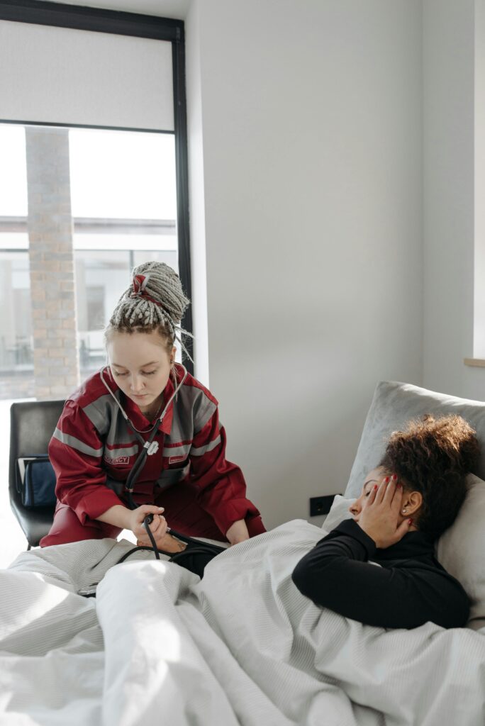 Paramedic providing healthcare assistance to a sick woman in a bright room.
