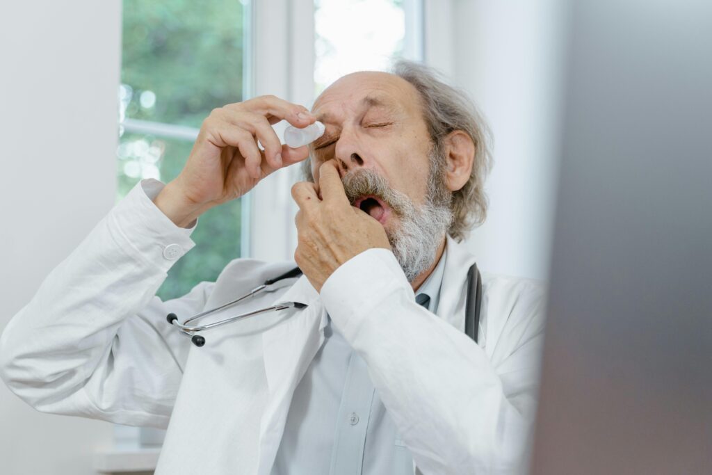 Elderly doctor applying eye drops, emphasizing eye care and senior health.