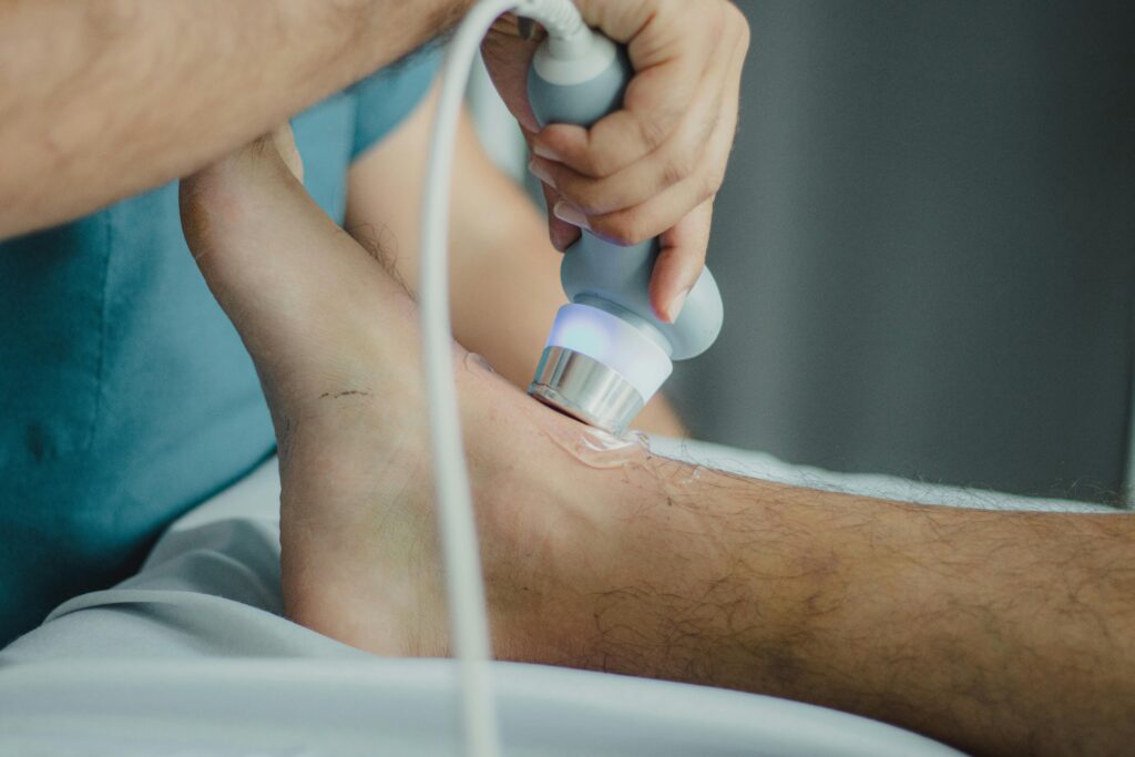 Professional physiotherapist using ultrasound device for leg treatment.