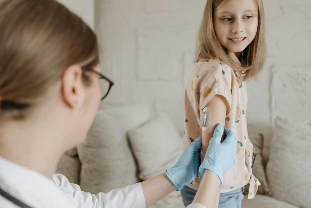 A young girl receives an insulin checkup from a medical professional at home, managing diabetes.