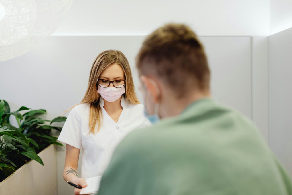 A medical professional with a face mask talking to a patient in a clinic setting.
