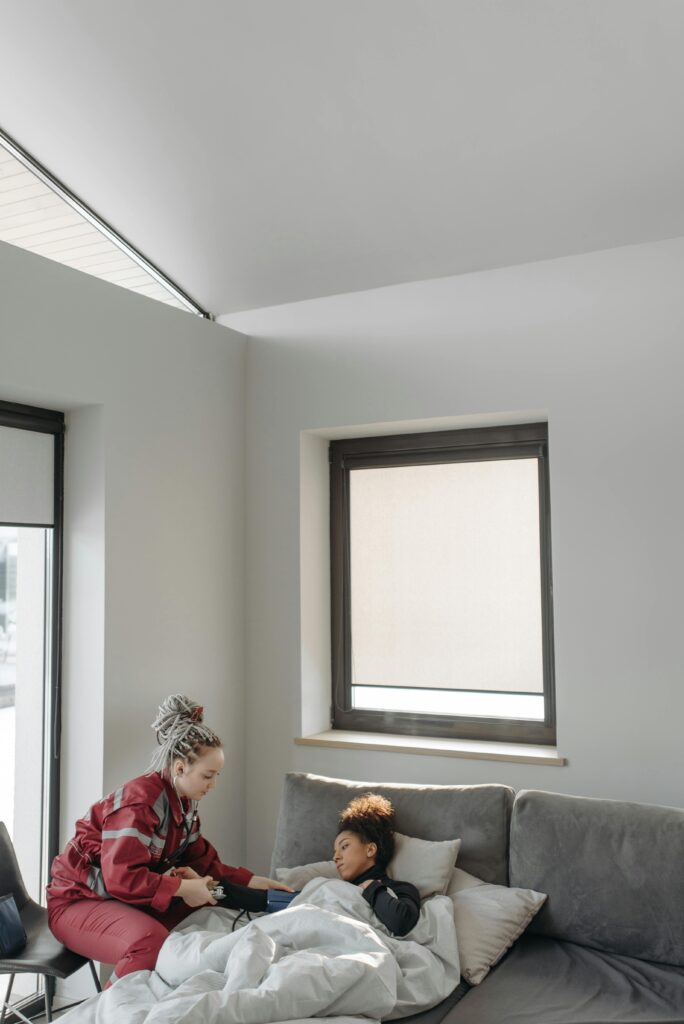 A paramedic checking a patient's vitals in a bright living room.