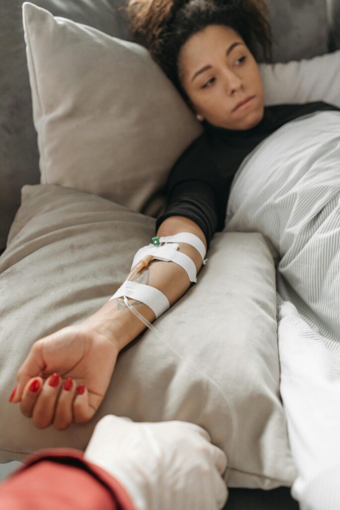 Woman lying in bed with medical tubes, depicting recovery or illness in an indoor setting.