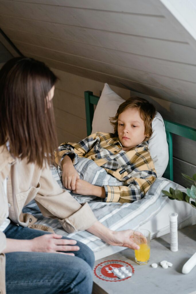 A concerned mother tends to her sick son lying in bed, offering care and comfort.