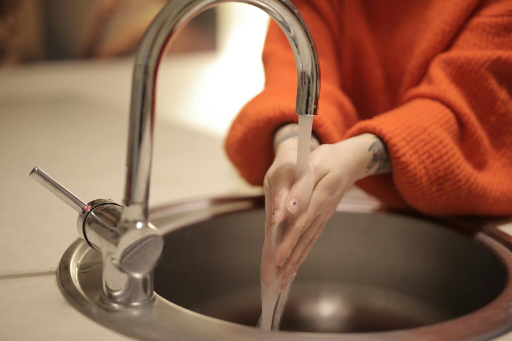 Close-up of hands washing under running water in a sink for hygiene. Perfect for health and cleanliness concepts.