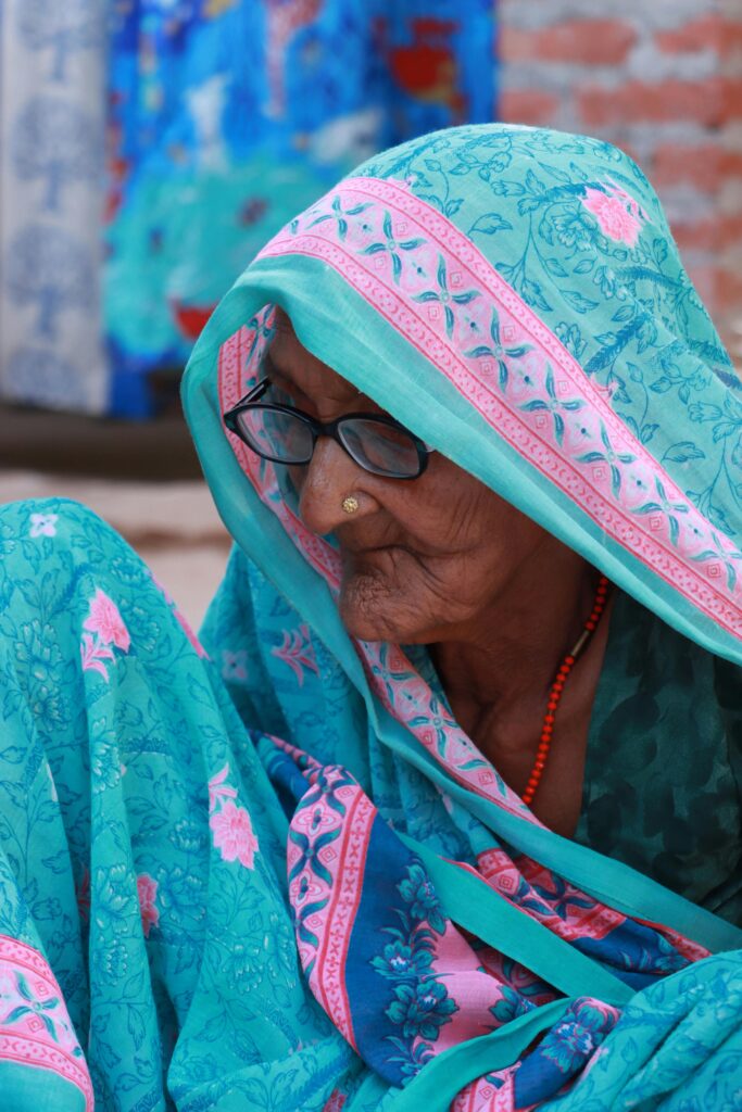 Side view of a senior woman in a colorful sari and hijab, portraying cultural elegance.